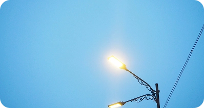 A lit streetlamp glows against a clear blue sky, with a utility pole and power line visible on the right side of the image.